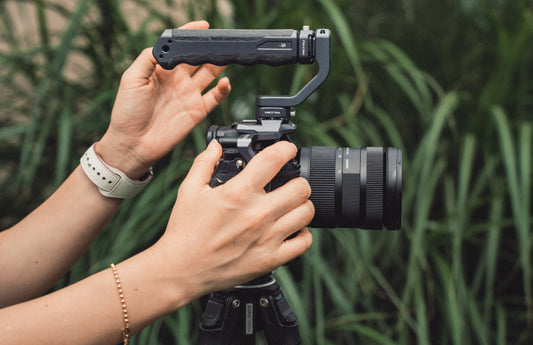 The image shows a camera setup with an external handle attachment, which is commonly used for enhanced control and stabilization in photography or videography.