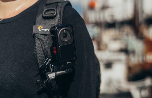 An action camera mounted on a backpack strap using a specialized mount