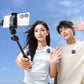 Couple taking a selfie with smartphone on tripod against a clear blue sky.