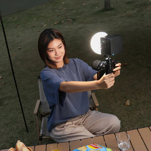 Photographer using compact Ulanzi LED light for evening outdoor shoot with camera rig.